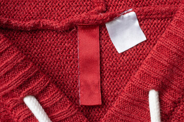 Blank laundry care clothes label on red knitted fabric texture background