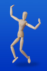 Dancing wooden toy figure on blue
