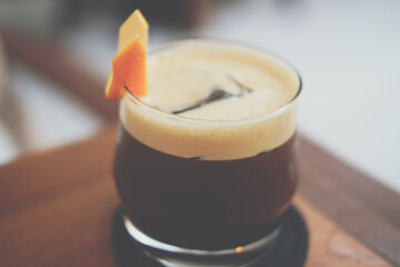 iced coffee mixing with orange syrup garnished with orange peel