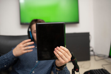 a young caucasian businessman holds a smart tablet in his hand and talks to someone. a young businessman in a blue shirt in his office