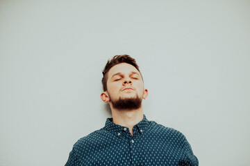 a stressed caucasian businessman wearing a blue shirt and prescription glasses grabs his head and gets annoyed in his office.