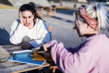 Shocked woman with hand on face while looking a best friend diary