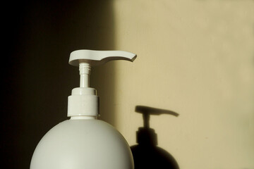 plastic white dispenser of a large volume of a container with cream and a shadow on the wall from it