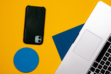 Laptop and mobile phone on blue yellow background