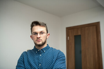 Obraz premium a portrait of a young caucasian businessman wearing glasses standing and posing for a picture. white background.