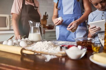 Concentrated kids making dough with their caring grandmother