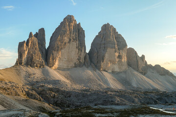 Golden hour in the Tre Cime di Lavaredo (Drei Zinnen) in Italian Dolomites. The mountains are reflecting golden sunrays. There is a lot of landslides and lose stones around. Natural wonder. Sunset