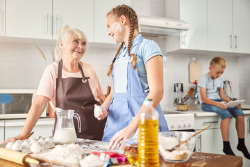 Happy girl and her smiley grandmother posing in kitchen