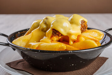 Patate fritte tagliate grossolanamente con polpettine di carne e fonduta di formaggio