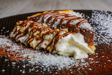 Torta al cioccolato con cocco guarnita con cioccolato fondete, granella di nocciole e panna