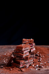 Organic food snack tasty sweet dessert milk dark chocolate bar macro closeup broken slide piece and fruit orange raspberry hazelnut nuts on cocoa cacao powder wooden table for new year Christmas gift