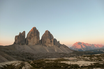 Golden hour in the Tre Cime region, Italian Dolomites. The mountains are shining with pink and orange. Sunrise in high mountains. Morning haze. Lower parts of the valley covered with shadow. New day