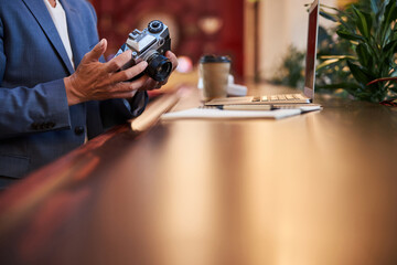 Elegant gentleman is inspecting his photo-camera indoors