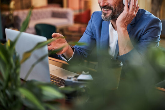Pleased gentleman having a video-call on his laptop from a hotel lobby