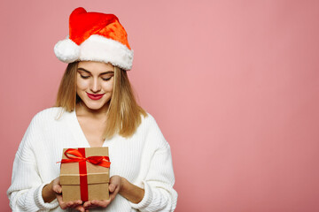 Portrait with copy space, empty place of pretty charming elegant girlfriend celebrating christmas, opening packed gift box isolated on pink background