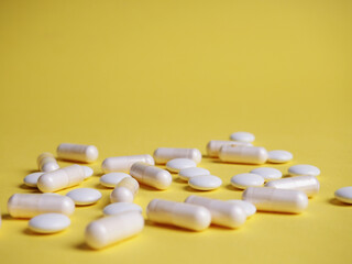 a lot of different white tablets on a yellow background, the concept of health and medicine