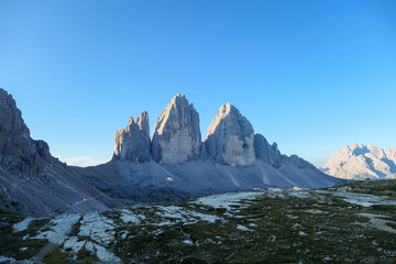 A panoramic capture of the Tre Cime di Lavaredo (Drei Zinnen) and surrounding mountains in Italian Dolomites. The mountains are surrounded by thick clouds. Early morning in the mountains. Daybreak