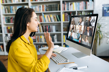 Online education. A female student learning online at home, she waving hand to other students or...