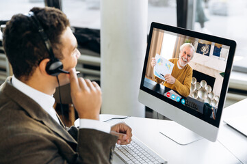 Video communication. Successful businessman or manager with headphones discuss with mature business...