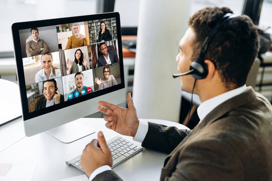 Online video conference. Successful young adult businessman or manager with headphones discuss with colleagues by video call about financial graphs and strategy and another working moments
