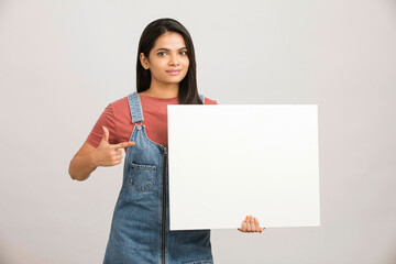 Cheerful attractive young women holding white board on white.