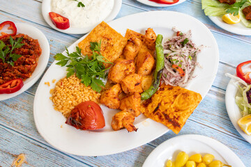 chicken shish kebab in a plate with appetizers. top wiev