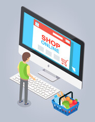 Online store concept. Male buyer selects a product on a store website on a computer. Internet shopping order products from home with delivery. Man in casual wear and supermarket basket with products