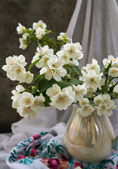Naklejka na ściany i meble Jasmine flowers in a white vase. Stillife with spring flowers.