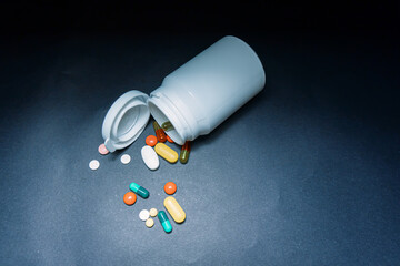 Medical bottles and medication pills spilling out on to pastel blue background. Top view with copy space. Healthcare, pharmacy