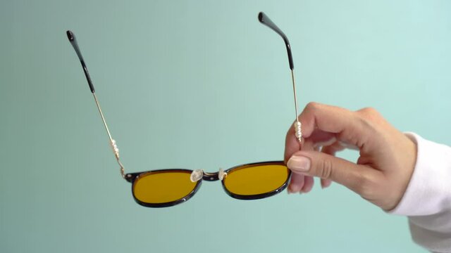 Vertical shot. Female Hand holds Stylish Glasses on a blue background.
