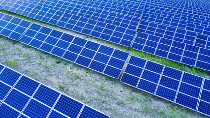 Background of solar panels array as seen from above the modern static solar power station. Green...