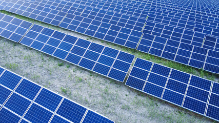 Background of solar panels array as seen from above the modern static solar power station. Green...