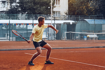 Obraz premium Young handsome man playing tennis on the tennis court
