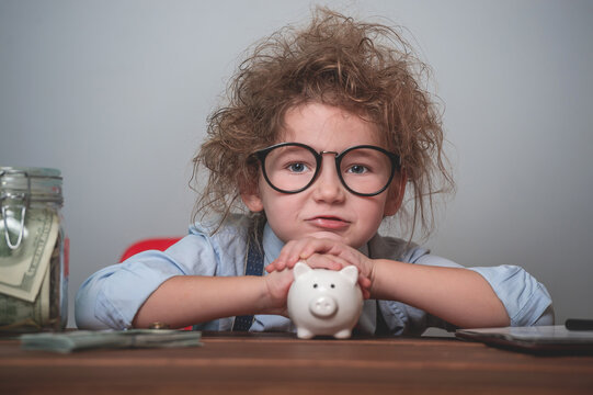 Kid with piggy bank. Portrait of little businessman. Child in glasses counting money. Back to school. Education for child how to be rich when grow up. Retro filter