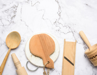 wooden kitchen utensils on white marble table, top view
