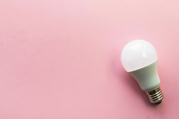 LED light bulb on pink background. Saving energy and environment concept. Flat lay, top view with copy space.