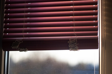 Blinds on the window. Protecting the window from sunlight. Blinds on the window frame. Red blinds.