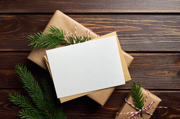 Greeting card mockup with christmas gift boxes and fir tree branches on dark wooden background