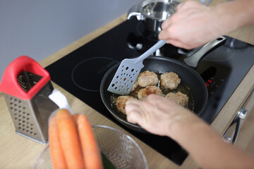 Cooking fried minced meat patties on electric stove in kitchen at home. Professional equipment and built-in kitchen appliances.
