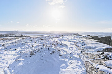 Fototapeta na wymiar A balnket of snow lit by an early morning low sun in the Derbyshire Peak District.