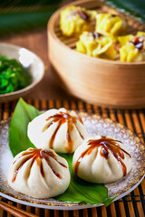 Dumplings set Xiao long bao and Shao mai in bamboo steaming basket and chopsticks on bamboo mat. Selective focus. Asian food menu.