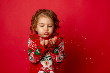little girl  blowing on snow red background Studio new year,christmas 