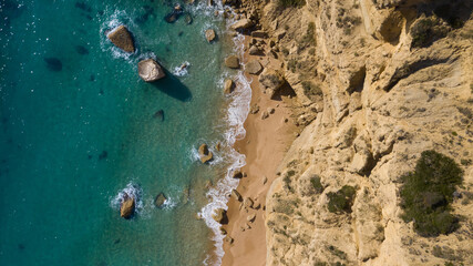 Top view from above of blue transparent water next to a sand and a cliff in Barbate, Spain