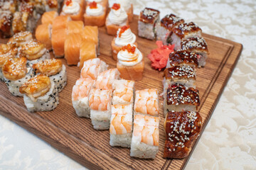 Different types of delicious and juicy sushi and rolls on a wooden board