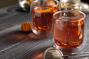 Glass teapot and glass cups of fruit tea on wooden background
