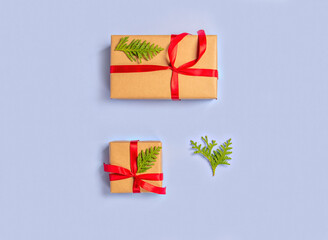 Gift boxes wrapped with paper kraft, red ribbon, thuja twigson a light background. Top view. Presents for the holiday, Christmas.