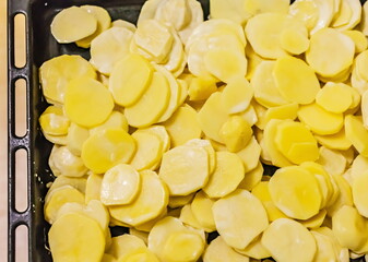 Sliced potatoes with mayonnaise on a baking sheet closeup