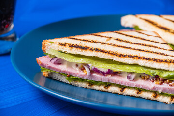 Ham and greens sandwich on a blue background.