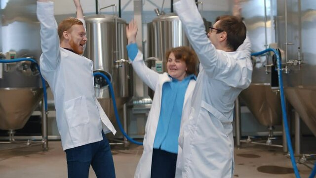 Team of brewers in white coat putting hands together and embracing