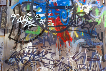 A wall damaged by multicolored paint, graffiti, urban vandalism